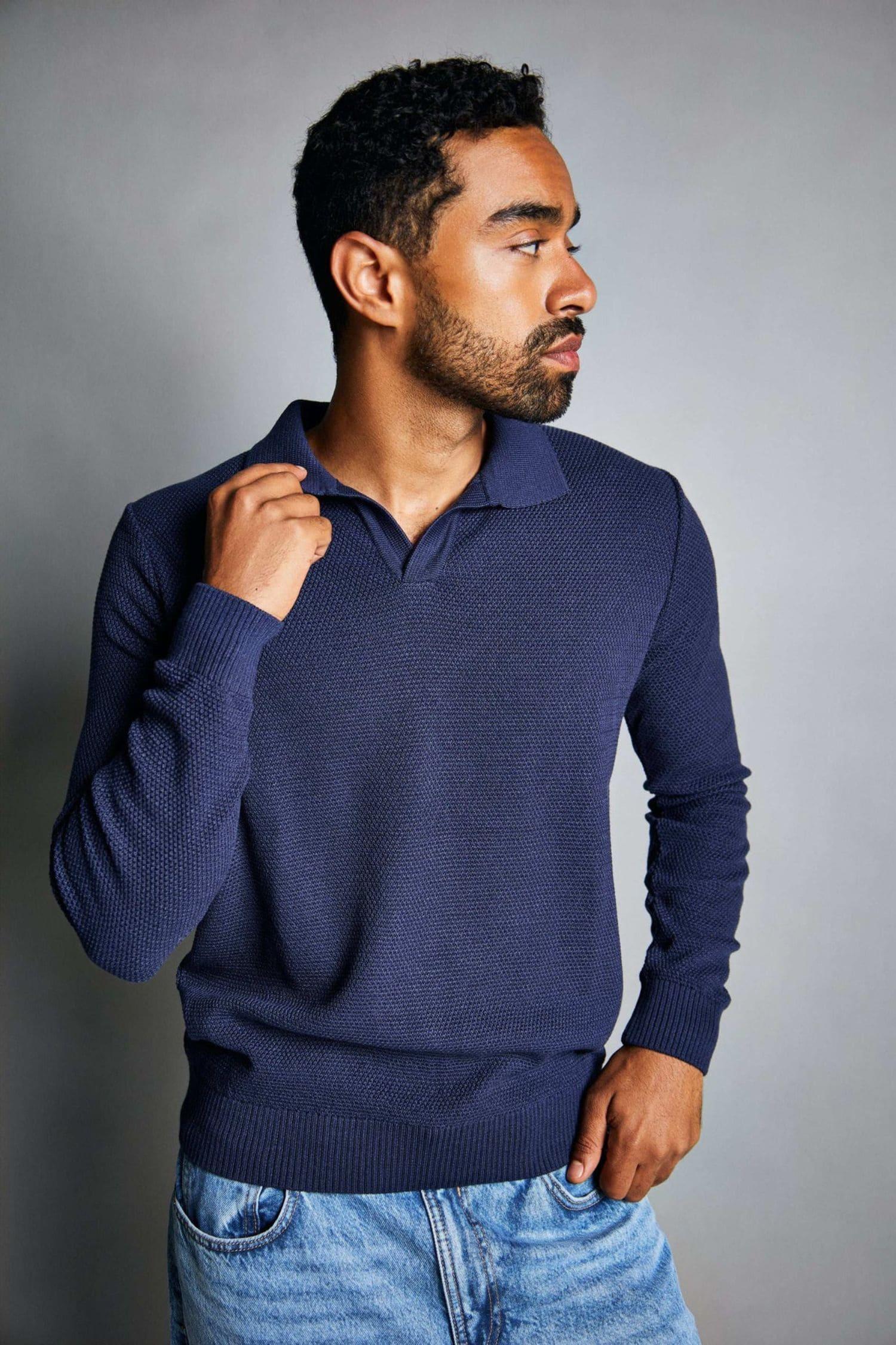 Hombre con suéter azul tejido de punto y jeans claros, moda masculina elegante.